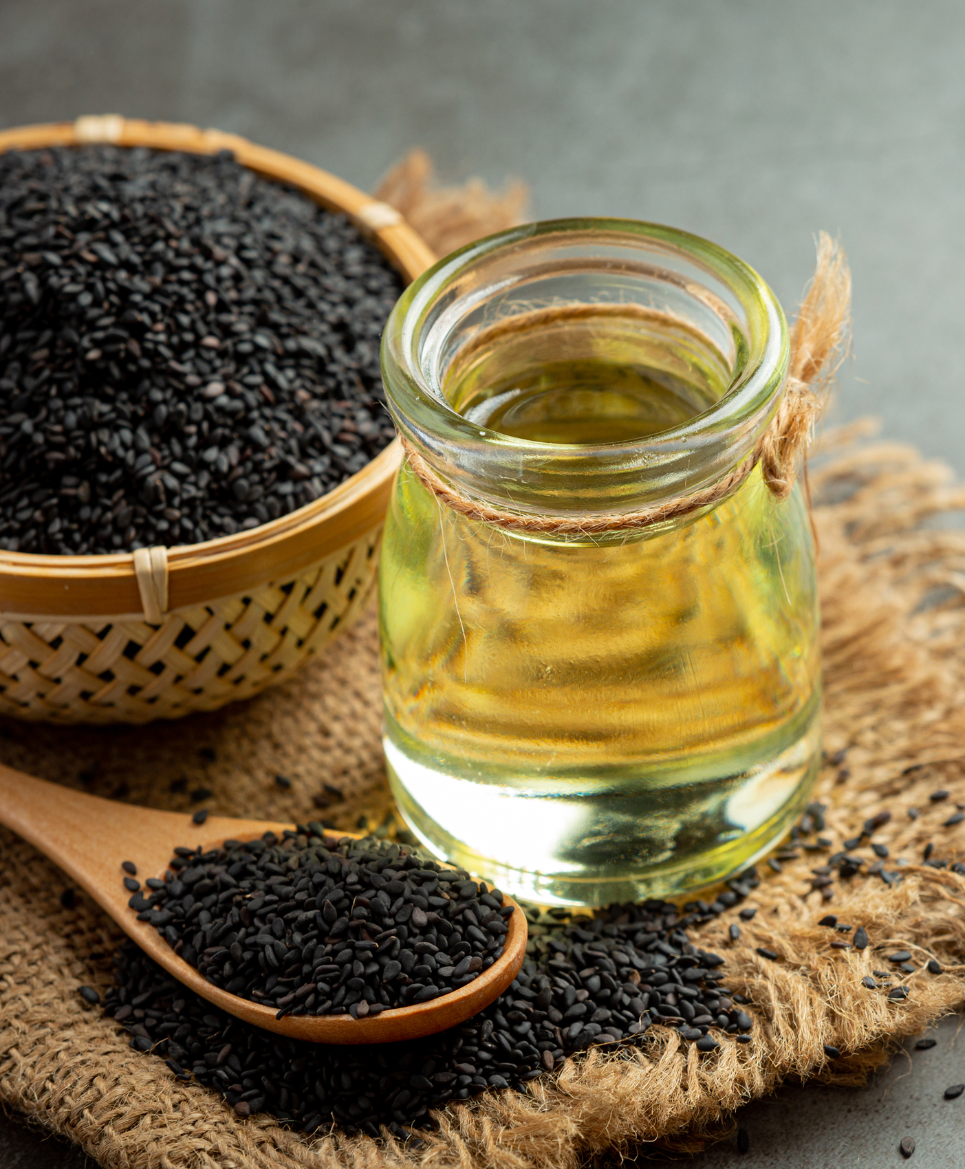 Olej sezamowy i surowe czarne nasiona sezamu na ciemnym tle